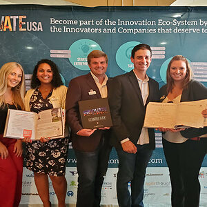 3 women and 2 men in front of banner, holding Innovate USA books at Innovate USA Launch party.